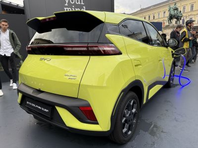 Rear view of a yellow electric hatchback charging with modern tail lights