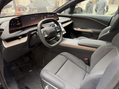 Wide digital dashboard and ergonomic seats in electric vehicle interior.
