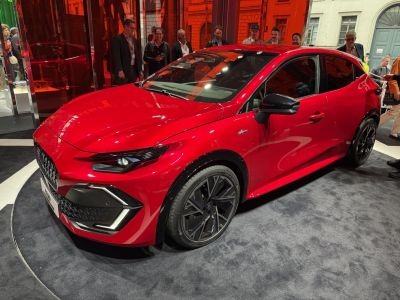 Sporty red hatchback with futuristic headlights and unique aerodynamic wheels.