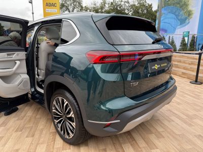 Rear view with distinctive taillights, open door, stylish wheel rims.