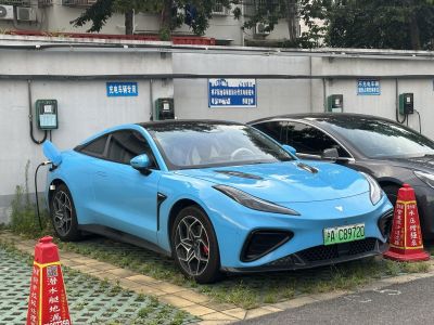 Blue electric coupe charging at a station