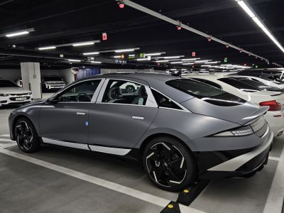 Rear side view of sleek electric sedan with futuristic wheels and aerodynamic silhouette.