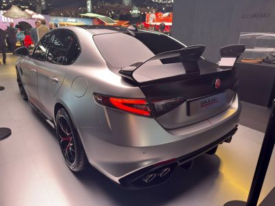 Rear view of a matte finished sedan with carbon fiber wing and quad exhaust