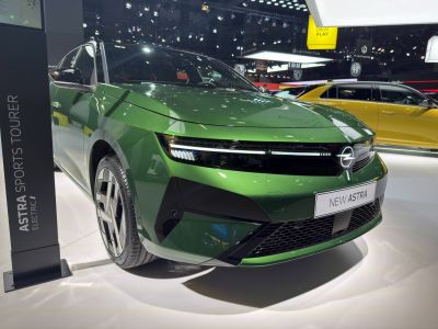 Front close-up of green electric vehicle with LED headlights and modern grille