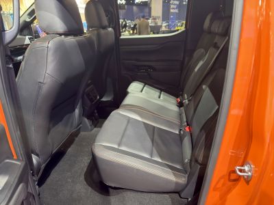 Rear seat interior with leather upholstery and orange stitching in a spacious vehicle cabin