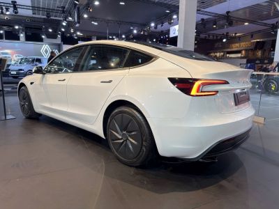 Rear-side view of a white electric sedan with LED taillights and aerodynamic wheels