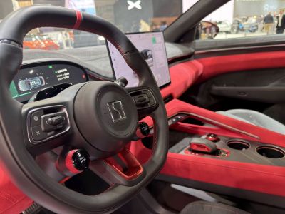 Modern digital dashboard and steering wheel with control knobs in red-accented interior
