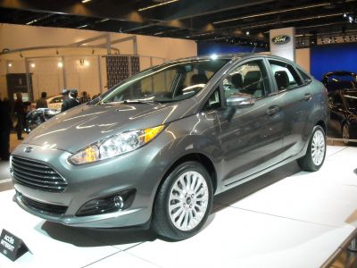 Front and side view of a silver compact sedan with sleek headlights and pronounced grille.