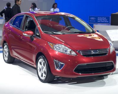Red sedan with chrome grille and five-spoke alloy wheels