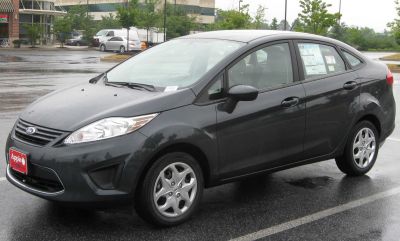Black sedan front side view with headlight and alloy wheel