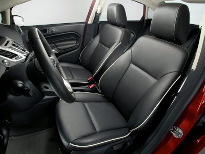 Black leather car seats with white stitching and a textured steering wheel.