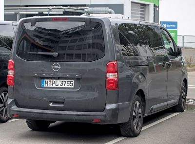 Rear view of a large passenger van with tinted windows and vertical taillights