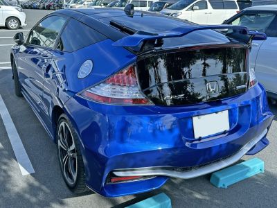 Rear view of sporty compact hatchback with spoiler and hybrid badge