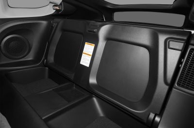 Rear interior storage compartment with integrated speaker and warning label