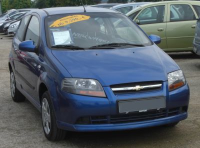 Front view of blue 3-door hatchback with headlights and grille