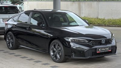 Front-side view of sleek black sedan with modern headlights and prominent grille