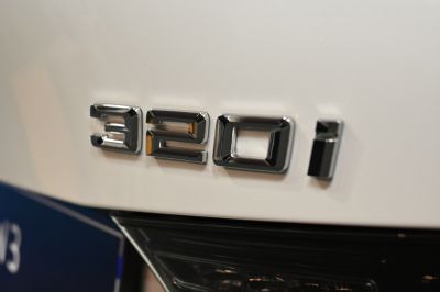 Close-up of the 320i rear badge on a white surface