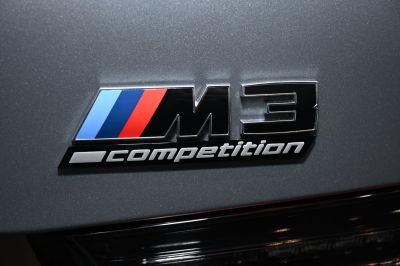 Close-up of BMW M3 Competition emblem with M tricolor stripes