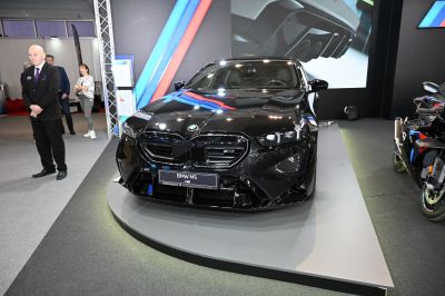 Glossy black luxury sedan front with aggressive grille and sporty headlights.