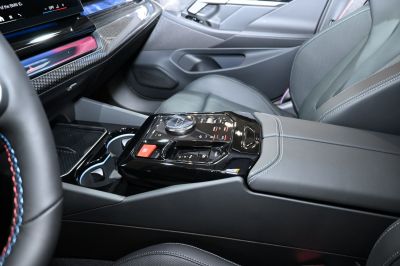 Central console controls with gear selector and cup holders in luxury car interior.