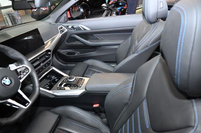 Luxury leather seats with blue stitching and advanced center console controls.