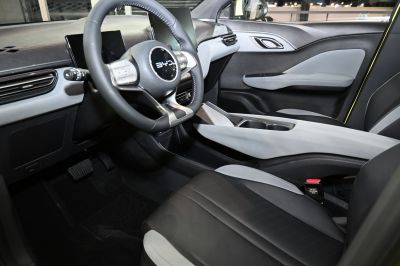 Modern car interior with steering wheel, digital displays, and front seat.