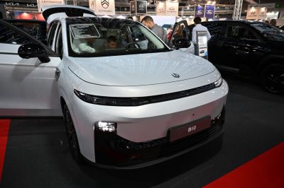 White vehicle front with sleek lights and open doors revealing interior
