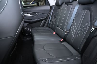 Black leather rear seats with detailed white stitching and seat belts.