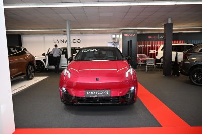 Front view of red vehicle with sleek LED headlights and prominent grille.