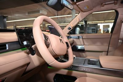 Beige leather interior with digital dashboard and steering wheel.
