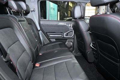 Rear black leather seats with red stitching inside a vehicle
