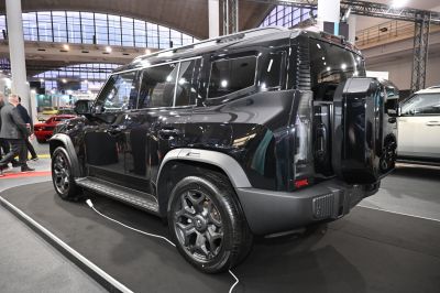 Rear side view of a black SUV with spare tire mount and electric charging cable
