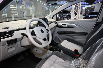 Modern electric car interior with steering wheel, touchscreen, and fabric seats