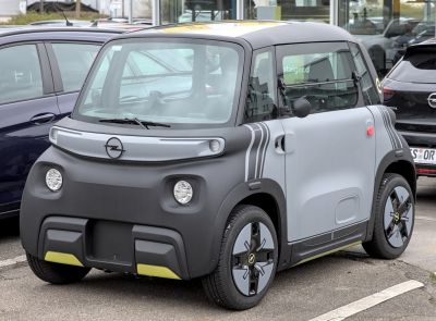Compact electric urban vehicle with modern minimalist design and distinctive headlights.