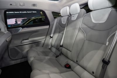 Spacious light gray leather rear seats with seat belts in a modern car interior