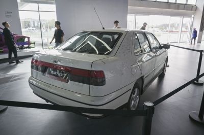 Rear view of a white sedan with tinted taillights and roof antenna