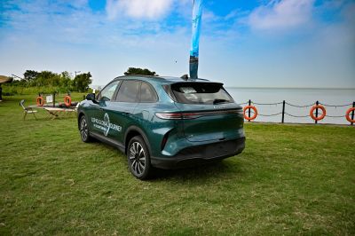 Rear and side view of an SUV parked on a green lawn near water.