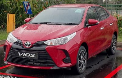 Red compact sedan front with sleek headlights and bold grille