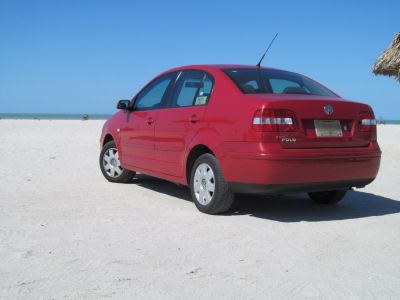 Rear side view of red sedan on sandy beach