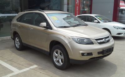 Front side view of beige SUV with roof rails and prominent headlamps