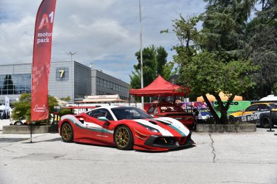Red and white racing livery with gold wheels on a track-prepared sports car.