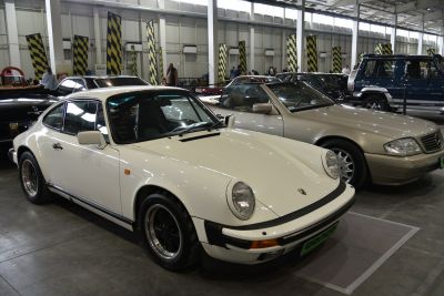 Vintage white sports coupe with round headlights and black alloy wheels.