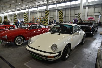 Front and side profile of classic 911 coupe, round headlights, showroom setting