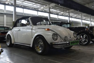 White vintage convertible with chrome deep-dish wheels and rounded headlights