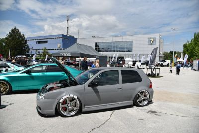Lowered gray hatchback with opened hood and chrome 5-spoke wheels