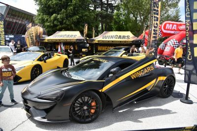 Matte black McLaren 570S with yellow Wincars livery and butterfly door open.