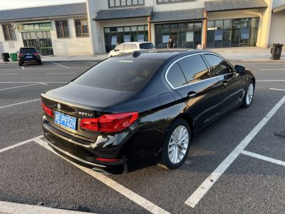 Rear exterior of sleek black luxury sedan with taillights and alloy wheels