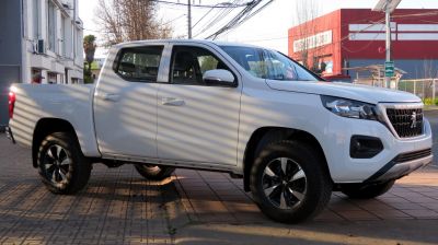 Side view of white four-door pickup truck with rugged tires