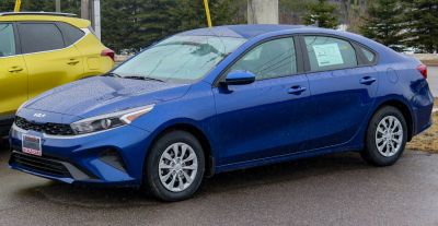 Blue sedan with modern headlights and alloy wheels viewed from front-side.