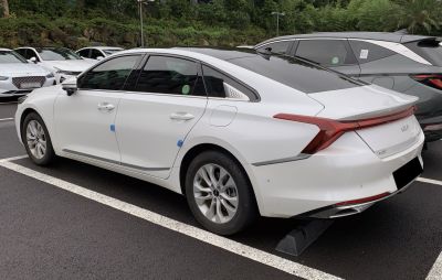 Rear side view of a modern white sedan with panoramic roof and integrated taillights